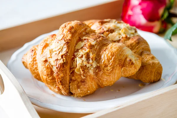 Läckra färska croissanter med kaffe och rose — Stockfoto