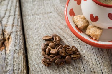 Coffee in white cup with hearts, beans