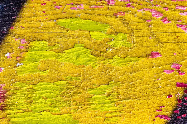 A fragment of colorful graffiti painted on a wooden board with peeling paint close-up. Abstract background for design.