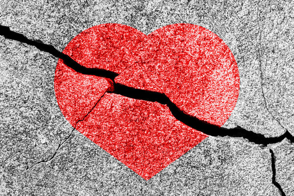 Red heart on a cracked texture. The concept of broken heart, end of love and disappointment.