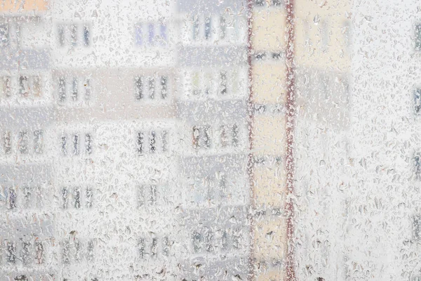View through a rainy window on a blurred house. Bad rainy autumn weather concept.