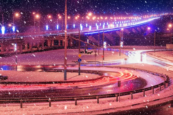 冬夜在桥上行驶的汽车前灯的痕迹 被降雪中的灯笼照亮 湿沥青路面反射的光 — 图库照片