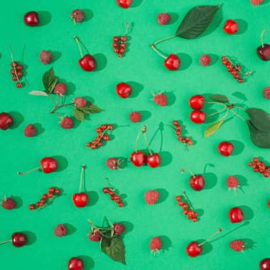 Yeşil arka planda organik kırmızı meyveden yapılmış yaz yerleşimi. en düşük düzlük.