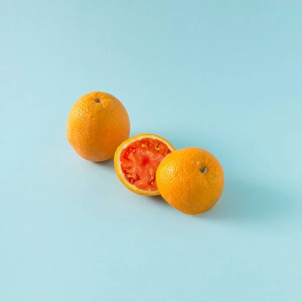 Juicy orange cut in half ,combined with tomato. funny concept.creative idea on pastel background.