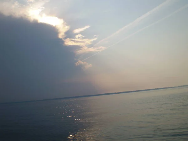 Gökyüzünün sudaki yansıması, uzak bir sahil, sıra dışı şekilli bulutlar..