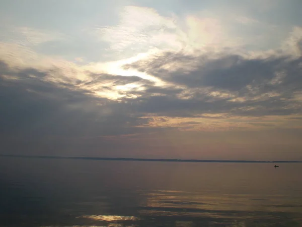 Gökyüzünün sudaki yansıması, uzak bir sahil, sıra dışı şekilli bulutlar..