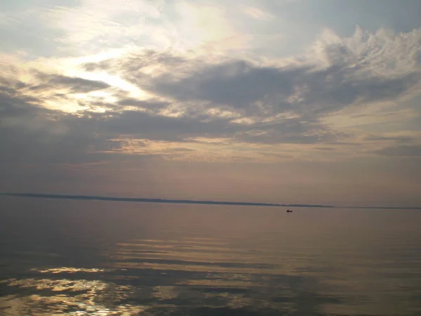 Gökyüzünün sudaki yansıması, uzak bir sahil, sıra dışı şekilli bulutlar..