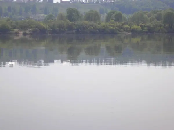 Gökyüzünün sudaki yansıması, uzak bir sahil, sıra dışı şekilli bulutlar..