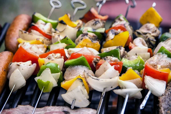 Výběr masa grilování nad uhlíky na přenosný gril s pikantní klobásy, hovězí steak, slaninu a kuřecí špízy — Stock fotografie