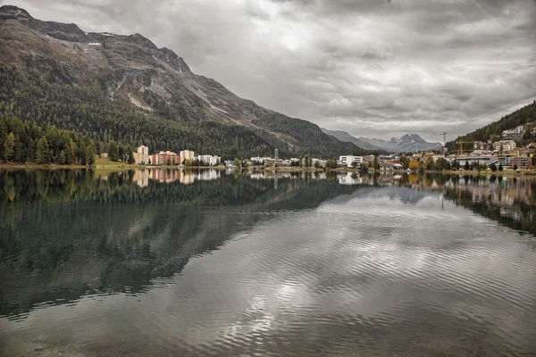 Mountain peaks, buildings and clouds reflecting in the lake at St. Moritz, Switzerland — Stok fotoğraf