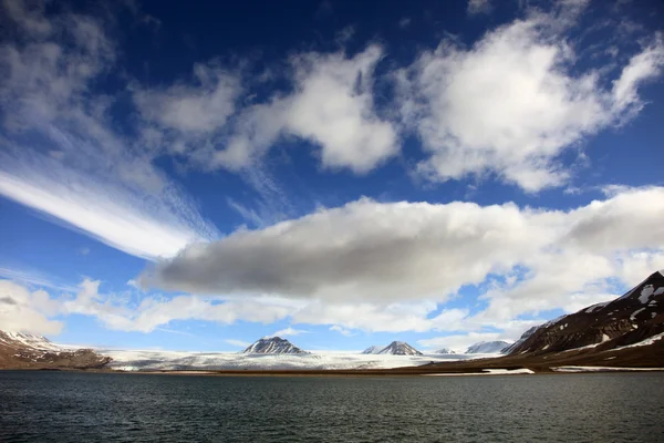 Panoramic view of mountain peaks and glaciers on a cloudy blue sky background in Svalbard, Norway — Stock Photo, Image