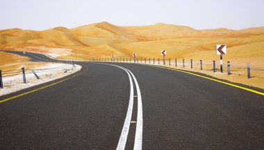 Winding black asphalt road through the sand dunes of Liwa oasis, United Arab Emirates clipart
