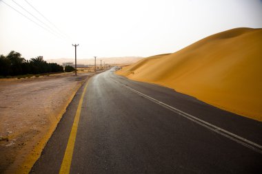 Kum tepeleri Liwa Oasis, Birleşik Arap Emirlikleri üzerinden dolambaçlı siyah asfalt yol