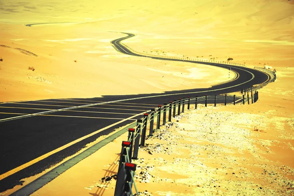 Enrolamento estrada de asfalto preto através das dunas de areia de Liwa oásis, Emirados Árabes Unidos — Fotografia de Stock