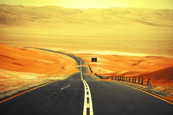 Strada asfaltata nera tra le dune di sabbia dell'oasi di Liwa, Emirati Arabi Uniti — Foto Stock