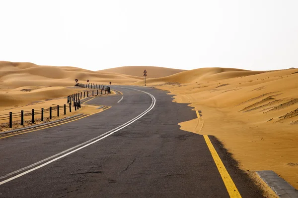 Winding black asphalt road through the sand dunes of Liwa oasis, United Arab Emirates — Stock Photo, Image