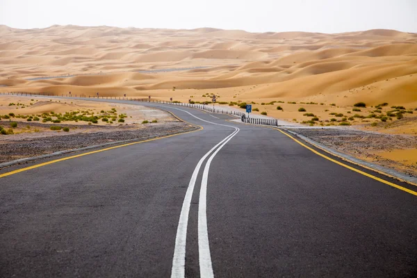 Enrolamento estrada de asfalto preto através das dunas de areia de Liwa oásis, Emirados Árabes Unidos — Fotografia de Stock