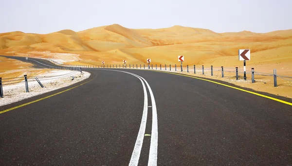 Kurvenreiche schwarze Asphaltstraße durch die Sanddünen der liwa oase, vereinigte arabische Emirate — Stockfoto