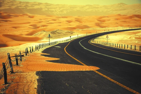 Winding black asphalt road through the sand dunes of Liwa oasis, United Arab Emirates — Stock Photo, Image