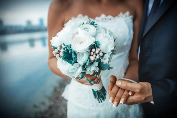 Gelin ve damat düğün buketi taşıyor.