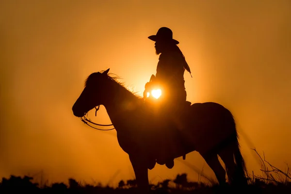 日没に銃を持って馬に乗ってカウボーイ — ストック写真