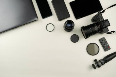 Beyaz deri arka planda profesyonel fotoğrafçının lensleri ve ekipmanlarıyla dijital kamera.