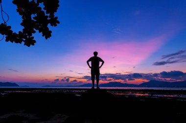 Şaşırtıcı doğanın güzel ışığına sahip bir adamın silueti Gün batımında dramatik gökyüzü ya da gündoğumu manzarası arkaplanı ön planda yapraklarla kaplı