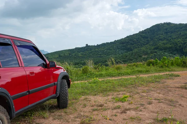 Red suv summer car and road in mountains Driving in forest dirt road Free space for your decoration Green forest background Countryside mood adventure