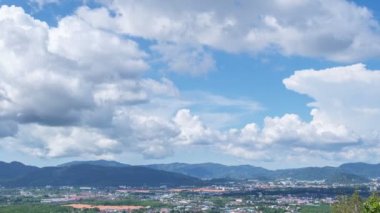 Beyaz Bulutlar Phuket City 'deki binaların üzerinden açık mavi gökyüzüne doğru ilerliyorlar. Hareket zamanı hızla ilerleyen beyaz bulutlar yüzer ve şekil değiştirir. Kabarık yumuşak bulutlar, dağda geçen yaz mevsiminde bulutlu zaman çizelgesi.
