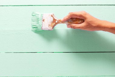 Kapatın ressam El, ahşap masa üzerine yeşil renk boyuyor. Fotokopi alanı, parlak yaratıcı tasarım iç mekan ve Tahta Yüzey Boyama.