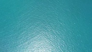 Hava görüntüsü İHA görüntüsü dalgalanır ve açık denizde dalgalanır, üst görünüm deniz kenarı, kamera suyun üzerinde uçar, su yüzeyinin bir görüntüsü, su yüzeyi drone kamera hareketinin arka planı