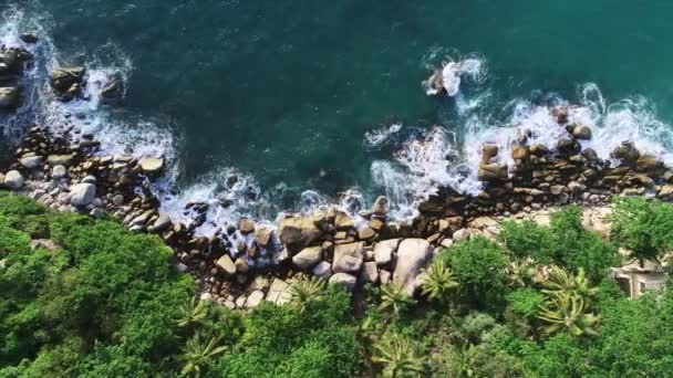 青い海の上からの空の石の岩の崖に対して波がクラッシュして熱帯海の空中ビューをトップオープン海 美しい海の表面の空中ビュードローンショット 海の高角度ビュー — ストック動画