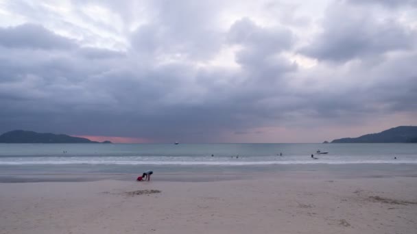 ビーチでの海の上の人や暗い雲のタイムラプスの動きパトンビーチで家族と楽しい一日の後に美しい夕日を楽しむ プーケットタイ — ストック動画