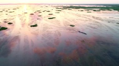 Uzun kuyruklu teknenin ya da güzel göldeki turist teknesinin ardından uçan hava aracı güneşin doğuşu ya da gün batımı ile gökyüzünün üzerinde