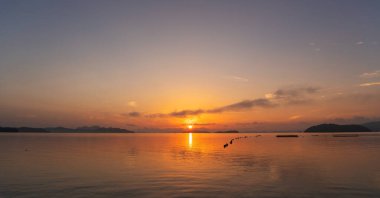 Güzel gün batımı ya da gün doğumu dramatik renkli gökyüzü bulutları sakin denizin üzerinde ve su yüzeyindeki yansıma tropikal ada inanılmaz doğa manzarası ve doğanın ışığı.