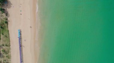 Turkuaz su yüzeyi ve köpüren okyanus dalgalarıyla beyaz kumsalın drone görüntüleri. Güneşli yaz gününde Cennet Adası 'nda tepeden aşağı hava manzarası. Web sitesi için güzel doğa arkaplanı