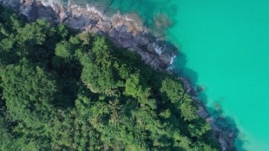 Mavi okyanusun yukarısındaki kayalıklara çarpan tropikal denizin yukarıdan aşağıya doğru uzanan dalgalı görüntüsü. Güzel deniz yüzeyi hava görüntüsü drone görüntüsü, yüksek açılı andaman görüntüsü.