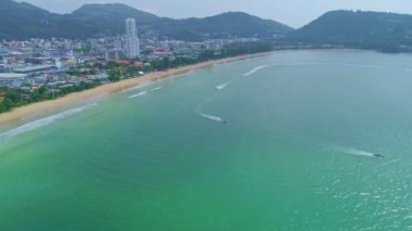 Phuket 'te Patong şehrinin güzel ve popüler bir plajı olan Air View 4K Patong Plajı' nda Patong Plajı 'nda Açık sezon yolculuk gününde denizlerde jet ski oynuyor.