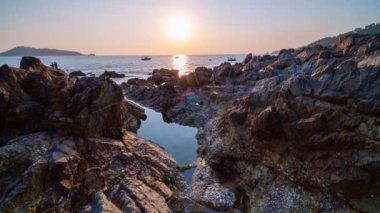 4K zaman ayarlı hareket kontrol kaydırma tavası ve güzel günbatımı altın ışık gökyüzü ön planda kayalar Phuket Tayland 'da inanılmaz deniz manzarası