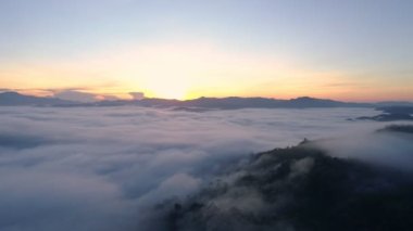 Yoğun sis bulutları dağların üzerinden ya da gün batımında hareket eder. Sis manzaralı hava manzaralı. Hava aracı yağmur ormanları üzerinde uçar. Güneş doğarken bulutlar ve sis. Doğa konsepti.