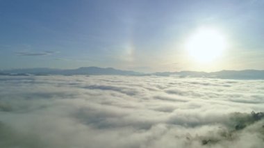 Yoğun sis bulutları dağların üzerinden ya da gün batımında hareket eder. Sis manzaralı hava manzaralı. Hava aracı yağmur ormanları üzerinde uçar. Güneş doğarken bulutlar ve sis. Doğa konsepti.