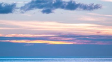 Gün batımında pürüzsüz renkli bulutların hızlandırılması ya da deniz dalgası üzerinde gün doğumu gökyüzü inanılmaz doğa video arka planı