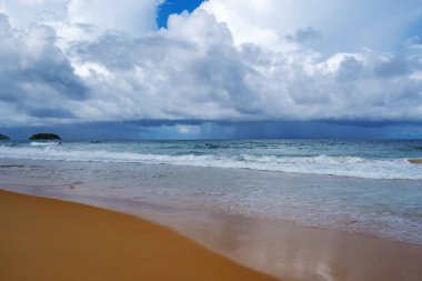 Okyanus 'un kıyı şeridi boyunca uzanan mesafesine sağanak yağış ile denizin üzerinde dramatik bir kara fırtına var. Pofet adasındaki sakin plajdan manzara. Çevre, iklim değişikliği kavramları..