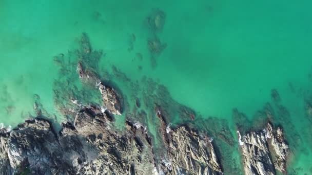 青い海の上からの空の石の崖に対して波がクラッシュして熱帯ターコイズブルーの海のトップダウン空中ビューオープン海の美しい海の表面の空中ビュードローンショット 高角度ビュー — ストック動画