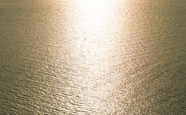 Aerial view Texture of Golden sea surface with small waves in the sea and Beautiful light sunset or sunrise over sea surface dark Golden sea texture background.