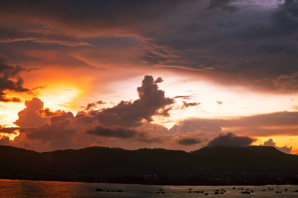 Dramatic clouds in sunset or sunrise over the mountains and the sea of Phuket islands in Thailand.