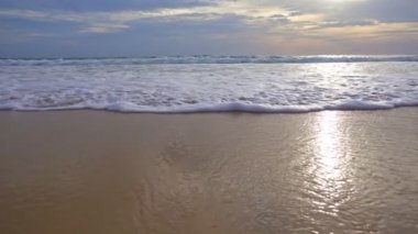 Kumlu sahile vuran dalgalar ve köpüklü dalgalar kumsala doğru süzülüyor güneş ışığı altında ya da gün doğumu manzarası manzarası