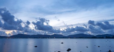 Kara bulutlar su yüzeyinde yansıması olan kara günbatımı bulutlarını sürüklüyor. İnanılmaz manzara deniz manzarası..