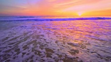 Dramatik deniz batımı ya da gün doğumu Yanan rengarenk gökyüzü ve parlayan beyaz dalgalar kumlu kıyılara çarpıyor Deniz yüzeyine güzel bir ışık yansıması İnanılmaz manzara ya da deniz manzarası