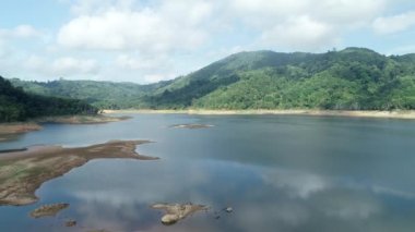 Kuru toprak ve orman yeşili desenli Dam Gölü Dağları 'nın hava görüntüsü güzel güneşli yaz havası Drone hava görüntüsü bulutları, doğanın sulama ortamını görüntüledi.